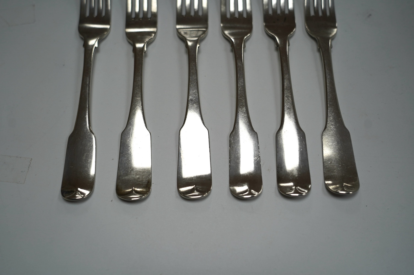 A set of four George III Irish silver fiddle pattern table forks, maker JS, Dublin, 1804, 20.9cm and a similar later pair, 12.8oz. Condition - poor to fair